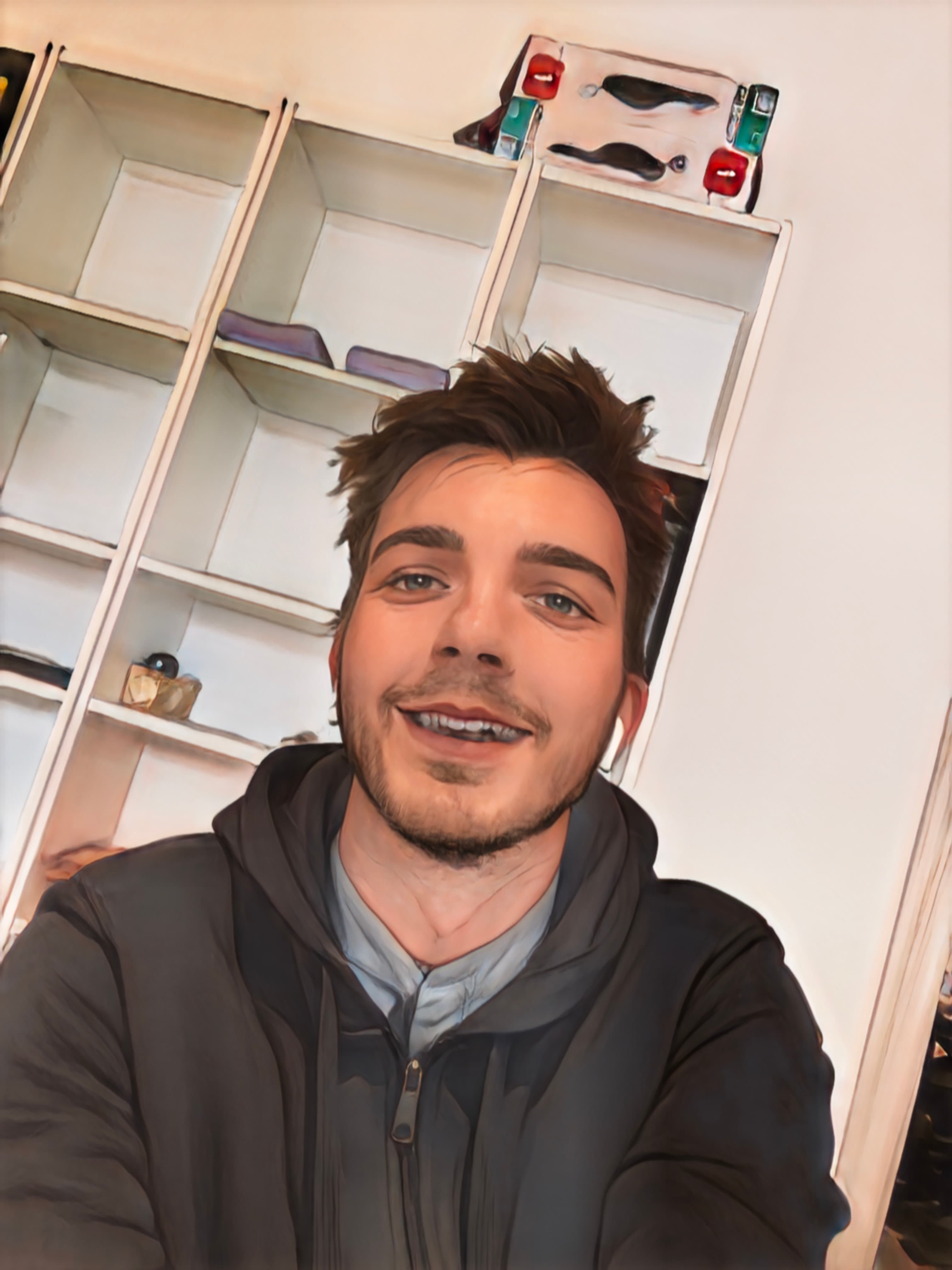 Mattia Paron sorride davanti a una libreria bianca